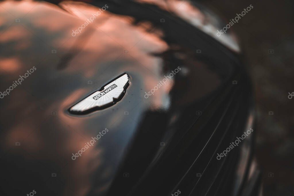 Milan, italy 28 october 2025: aston martin car emblem reflecting warm evening sky on a glossy black vehicle surface, highlighting automotive luxury and design