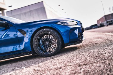 Vo, italyan 28 Ekim 2025: mavi bmw m4 spor coupe ön ve tekerlek ayrıntıları, performans tasarımı, fren diski, jant ve far güneş ışığı