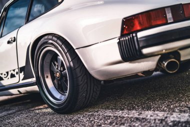 Vo, italyan 28 Ekim 2025: beyaz Porsche 911 klasik coupe yan detayı arka tekerlek, çamurluk, tampon ve egzoz borusunu açık havada güneş ışığı altında gösteriyor