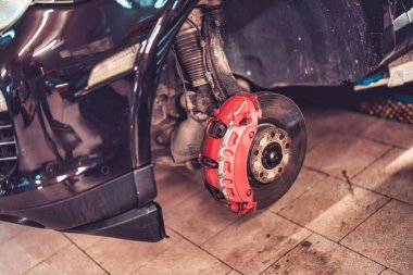 Roma, İtalya, 20 Kasım 2025: Bir oto servis garajında denetim ve bakım sırasında kırmızı fren kalibreli ve disk pervanesinin yakın çekimi, ayrıntılı metalik bileşen işi