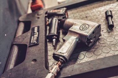 Roma, İtalya, 20 Kasım 2025: Hava destekli çarpma anahtarı ve araç gereçleri bir oto tamirhanesinde kirli metal tezgahta, endüstri ve bakımı gösteriyor.