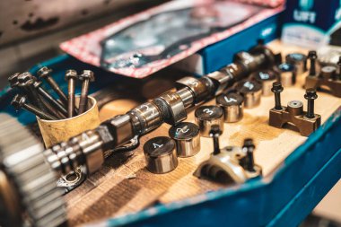 Roma, İtalya, 20 Kasım 2025: motor tamiri ve bakım için atölye tezgahına yerleştirilmiş kam mili, vana kaldıracı ve cıvatalar, otomotiv parçalarının yakın çekimi