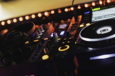 Rovigo, İtalya, 18 Aralık 2025: DJ konsolu kulaklıklar, faderler ve parlak kırmızı ve turuncu renkli düğmelerle karıştırarak parti atmosferi yaratıyor.