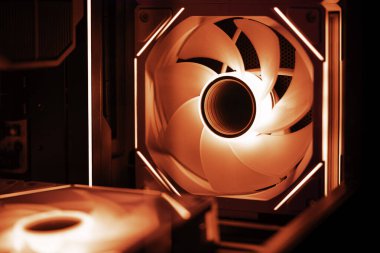 Kırmızı rgb bilgisayar kutusu pervanesi oyun masası içinde parlıyor, ana kart ve işlemci soğutucusunun üzerine neon ışığı dökerek yüksek performanslı donanım bileşenlerini etkili bir şekilde soğutuyor