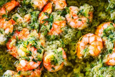 Sarımsak, otlar ve tereyağı sosuyla tavada cızırdayan karides, canlı, kremalı deniz ürünleri tabağının yakın görüntüsü aperatif ya da ana yemek için mükemmel.