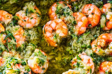 Canlı yeşil bitkisel sosta kaynayan karidesler fesleğen, sarımsak ve sebze karışımı sağlıklı, lezzetli bir deniz ürünleri tavası servis etmeye hazır..