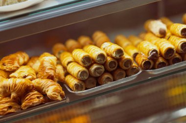 Krema ve katmanlı sfogliatelle ile dolu çıtır İtalyan çörekleri, altın kabukları ve lezzetli dolgularıyla baştan çıkarıcı bir fırın vitrininde güzelce düzenlenir.