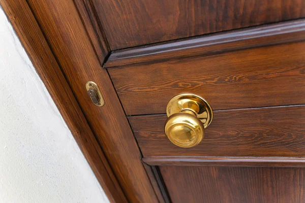 Parlatılmış pirinç kapı tokmağı ve ahşap bir kapının görünür kilidi, ev, güvenlik, mahremiyet ve klasik bir konut ortamının giriş ve çıkışını çağrıştıran yakın plan detay