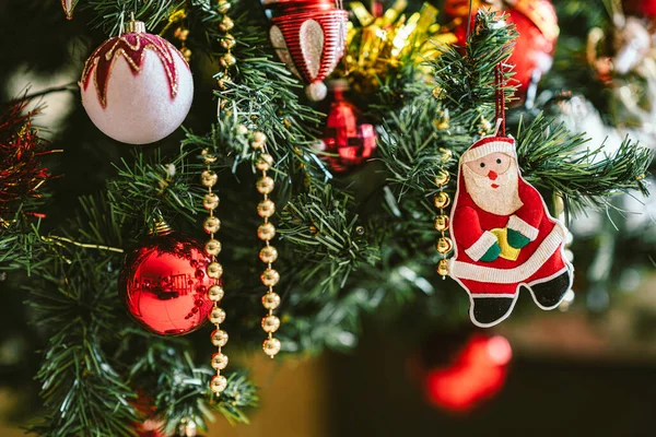 Geleneksel Noel Baba süsüsüyle süslenmiş Noel ağacı dalları, kırmızı mücevherler ve altın boncuklu çelenkler, neşeli bir tatil atmosferi yaratıyor.