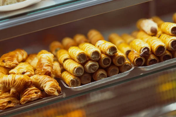 Krema ve katmanlı sfogliatelle ile dolu çıtır İtalyan çörekleri, altın kabukları ve lezzetli dolgularıyla baştan çıkarıcı bir fırın vitrininde güzelce düzenlenir.