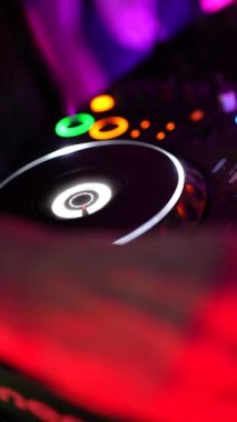 Roma, İtalya 2 Ocak 2026: Müzik çalmak için mikser ve pikabın kullanıldığı bir DJ 'in yakın çekimi. Renkli ışıklar ve düğmeler, karanlık bir kulüpte ses karıştırma konsolunda yanıp sönüyor.
