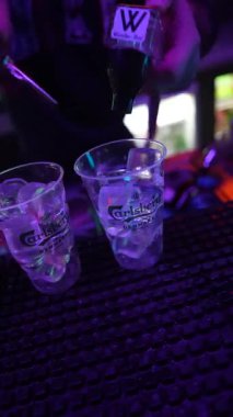 Roma, İtalya, 2 Ocak 2026: Profesyonel barmen canlı bir gece kulübü partisinde şişeden plastik bardağa karışık alkollü içecek dolduruyor.