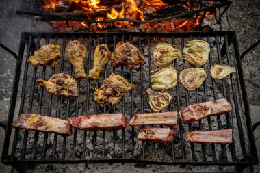Kükreyen alevler ve yanan kömürlerin üzerinde tavuk, pirzola, biftek ve sebze ızgara, arka bahçe partileri ve yaz şölenleri için cızırdayan açık hava barbeküsü