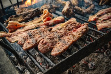 Parlayan közler ve alevler üzerinde mangal yapan etler, sıcak, kırsal bir yaz barbeküsü ya da arka bahçede barbekü için domuz eti ve sığır eti pişirmek gibi kıvrılan dumanlar.