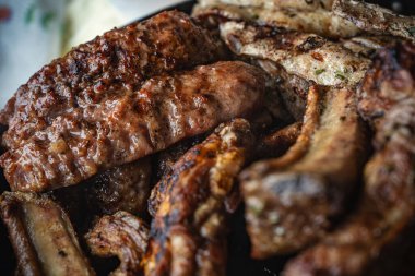 Domuz pirzolası, sosis ve ızgarada pişen çeşitli baharatlı et parçaları sağlıklı bir yemek için kömür izleri ve sulu dokular yaratır.