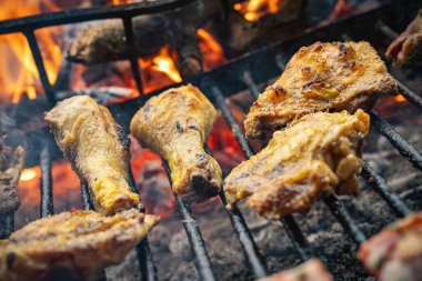Tavuk kanatları ve bagetler mangal ızgarasında pişiyor. Parlak kömür ve alevler üzerinde. Duman ve lezzetli bir yemek için hazır altın-kahverengi çıtır bir deri yaratıyor.
