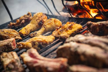Tavuk budu, kanat ve çeşitli domuz pirzolası da dahil olmak üzere karışık etler, mangal ızgarasında açık ateşte pişirmek, açık havada lezzetli bir aşçılık deneyimi yaratıyor.