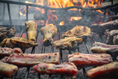 Sıcak ızgarada pişen tavuk budu, kanat ve kaburga kesimleri, duman ve ateş üreten, yaz pikniği, açık hava etkinlikleri ve geleneksel et hazırlıkları için mükemmel.
