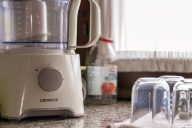 Roma, İtalya, 1 Ocak 2026: Kenwood gıda işlemcisi granit tezgahın üzerinde, parlak pencerenin yanında, doğrama, karıştırma ve günlük yemek hazırlama için temiz beyaz cihaz