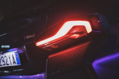 Roma, İtalya, 9 Ocak 2025: bm2 gece spor coupe, aydınlatılmış arka lambaya yakın çekim ve kentsel yansımalı belirgin rozet