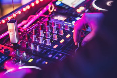 Roma, İtalya, 9 Ocak 2025: DJ el fader 'ı profesyonel ses karıştırıcı konsoluna ayarlıyor canlı bir gece kulübü müzik etkinliğinde neon pembe ışıklar, yakın çekim kontrol
