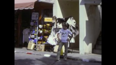 Mallorca, İspanya Haziran 1978: 1978 yazında İspanya 'nın kıyı kasabasında turistlerin güneşli bir sokakta yürüdüğünü ve alışveriş yaptığını gösteren arşiv görüntüleri
