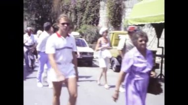 Palermo, İtalya, Haziran 1980: 1980 'lerde bir yaz günü tipik bir Sicilya caddesinde gezinen turistleri gösteren otantik vintage görüntüler