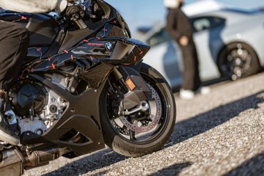 Imola, İtalya 01 Ocak 2026: bmw s1000 rr asfalt üzerine park edilmiş spor motosiklet, ön tekerleği, disk frenleri ve motor bileşenleri. Arka planda duran biri.