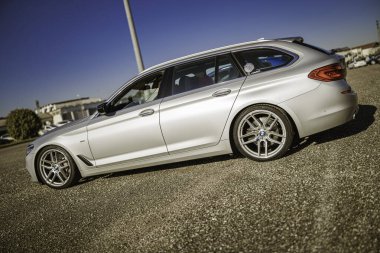 Imola, İtalya 01 Ocak 2026: modern gümüş bmw 5 serisi mavi gökyüzü zerafeti altında çakıl taşı üzerinde park edilmiş, lüks ve performans taşıyan premium station wagon..