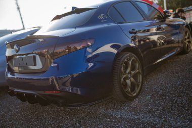 Imola, İtalya 01 Ocak 2026: Alfa Romeo Giulia idari spor sedan İtalyan lüks tasarımı ve performansını sergiliyor, altın tekerleklerle çakılların üzerine park edilmiş.