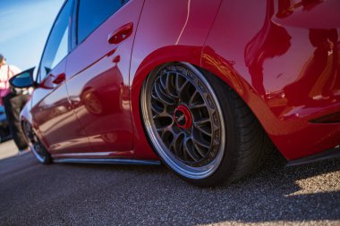 Imola, İtalya 01 Ocak 2026: Düşük profilli kırmızı özelleştirilmiş araba, kalın çanak kaplamalı market tekeri, ve parlak vücut boyası yansıması