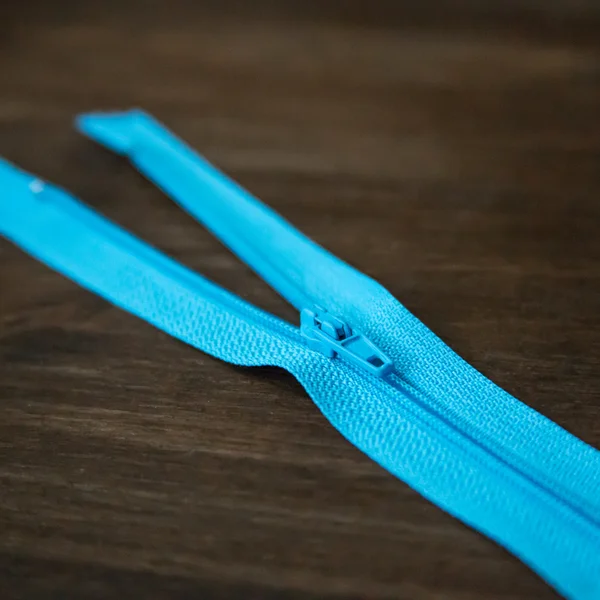 Blue zipper on dark wood background — Stock Photo, Image