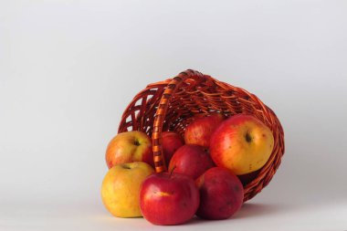 Beyaz bir arka planda el yapımı hasır bir sepette olgun elmalar. İzole bir hayat.