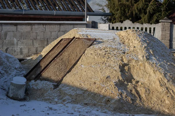 Construction of a private house. A pile of sand dusted with snow