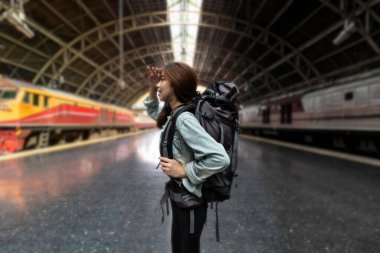 Kendine güvenen genç Asyalı sırt çantalı kadın tren istasyonunda yeni zorluklar arıyor. Yaz tatili yaşam tarzları