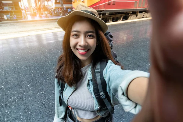 駅で写真や自撮りを撮るバックパック付きの魅力的な若いアジアの女性旅行者 旅行ライフスタイルのコンセプト — ストック写真