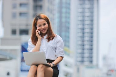 Ofis dışında iş için dizüstü bilgisayar kullanan kendine güvenen genç Asyalı iş kadını..