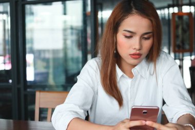 Ofisinde cep telefonu olan Asyalı genç bir iş kadını. Nesnelerin İnternet konsepti.