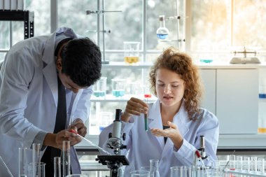 Modern laboratuvarda test tüpünde kimyasal sıvıyı inceleyen genç bir bilim adamı. Bilim ve tıp konsepti