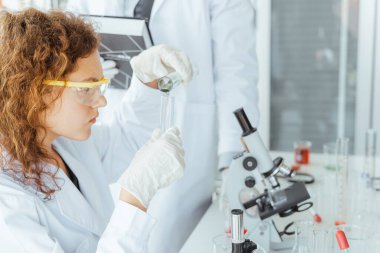 Genç bir bilim adamı modern kimya laboratuarında kimyasalları inceliyor. Bilim ve tıp konsepti