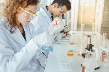 Genç bir bilim adamı modern kimya laboratuarında kimyasalları inceliyor. Bilim ve tıp konsepti