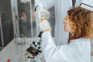 Genç bir bilim adamı modern kimya laboratuarında kimyasalları inceliyor. Bilim ve tıp konsepti