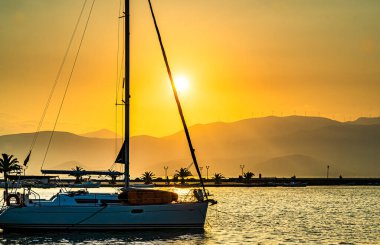 Yunanistan 'ın Nafplio kentinde gün batımı, limanda yolcu gemileri ve yatlarla