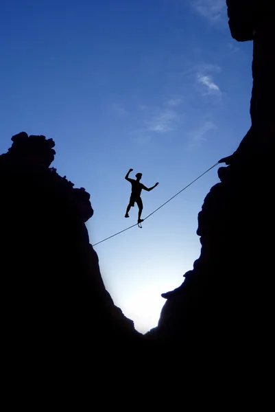 Mann läuft auf festem Seil über den Felsen — Stockfoto