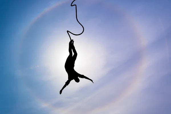 Silhouette of bungee jumper over blue sky background — Stock Photo, Image