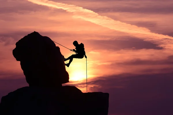 Homem escalador silhueta ao longo do pôr do sol brilhante — Fotografia de Stock