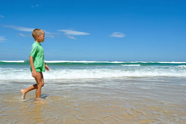 Ung pojke promenader längs vattenkanten — Stockfoto