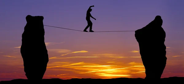 Silueta de un hombre caminando sobre la cuerda floja — Foto de Stock