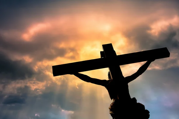 Cruz cristiana con la estatua de Jesucristo sobre nubes tormentosas —  Fotos de Stock