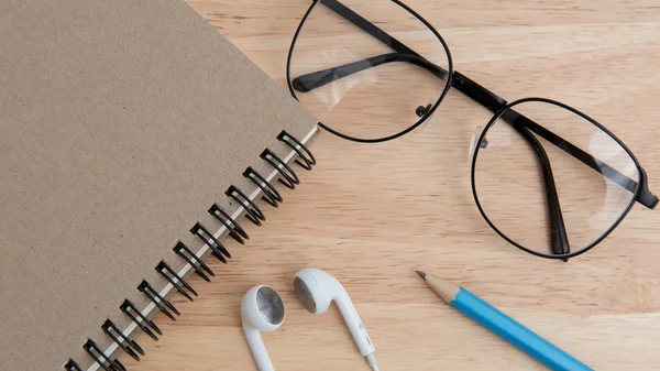 Ноутбук с карандашом, наушником и очками на столе — стоковое фото